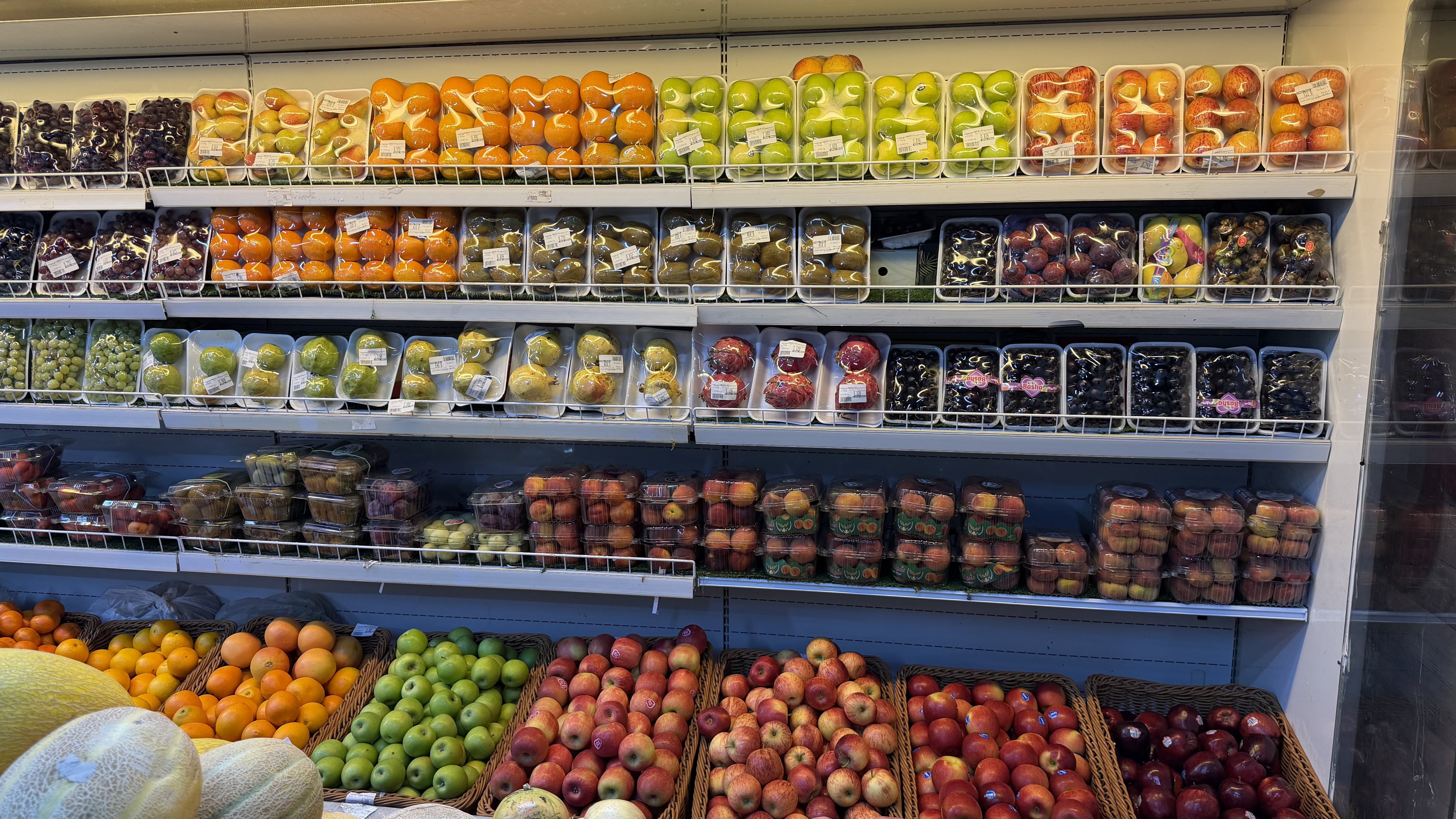 A stocked fruit and vegetable aisle in an Omani shop